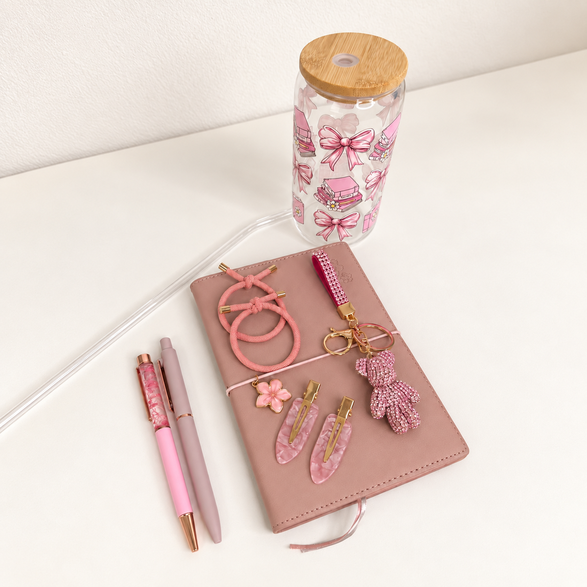 Pink bow bookish tumbler gift set with blush notebook, pink pens, hair clips, cord bracelets and beaded bear keychain